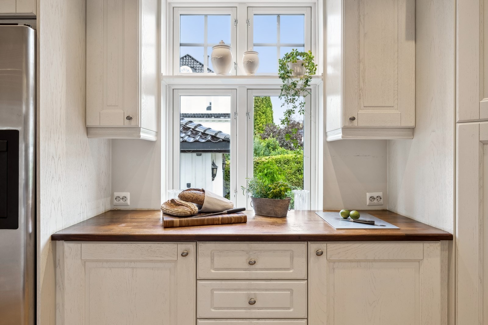 Kjøkken med profilert innredning, dels med glass, og benkeplater i heltre eik Galleribilde