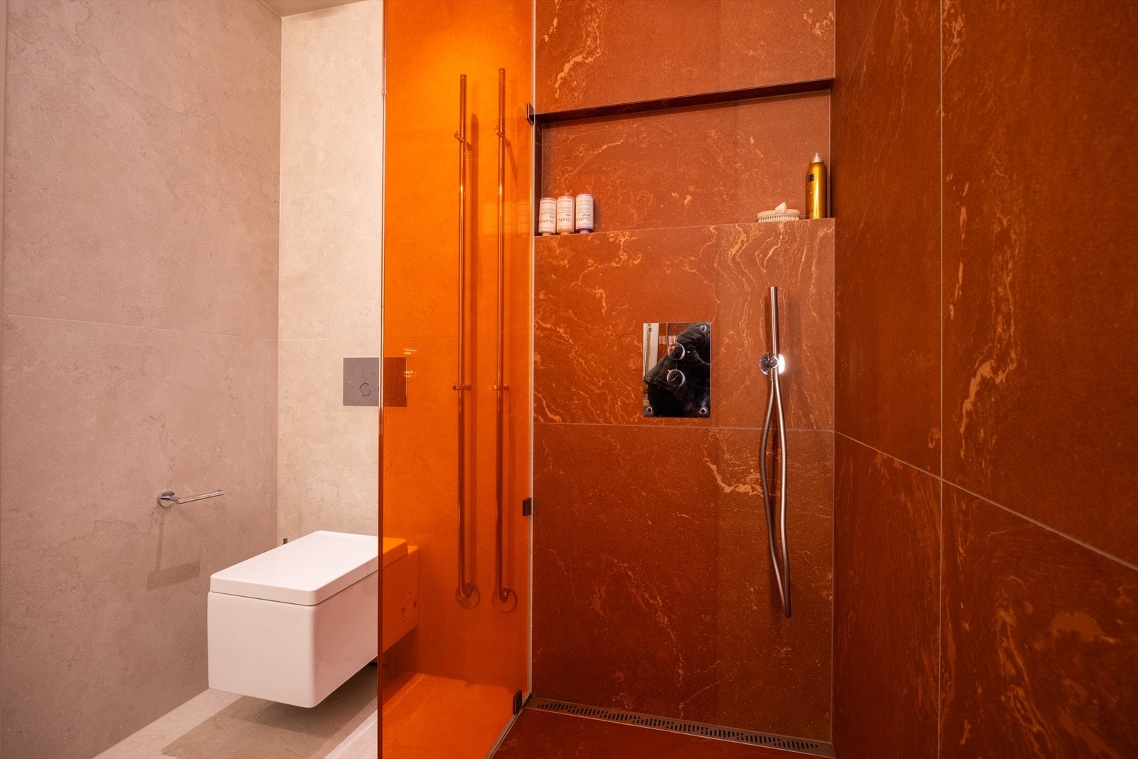 Badet er utstyrt med et veggmontert toalett, og i dusjnisjen finner du et dusjarmatur med både takdusj og hånddusj for en fleksibel og komfortabel dusjopplevelse. Galleribilde