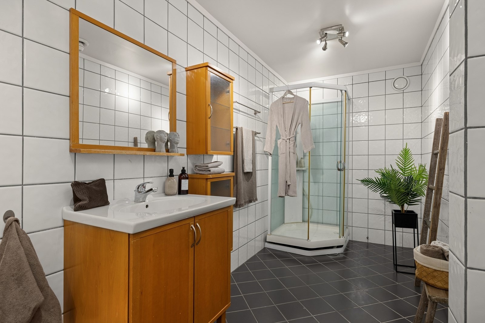 Baderommet er helflislagt og stilfullt innredet med servantskap, wc og dusjkabinett. Opplegg for vaskemaskin gir ekstra komfort og funksjonalitet. Galleribilde