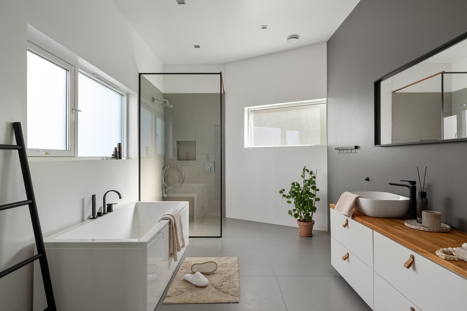 Lyst og romslig baderom med badekar, dusjhjørne og stilrene detaljer. Store fliser og god belysning gir et tidløst preg. Galleribilde