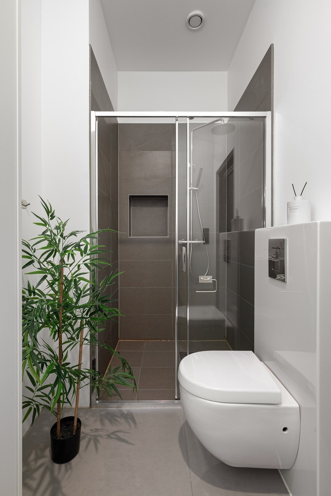 Stilrent bad med dusjhjørne, vegghengt toalett og fliser i tidsriktige farger. Galleribilde