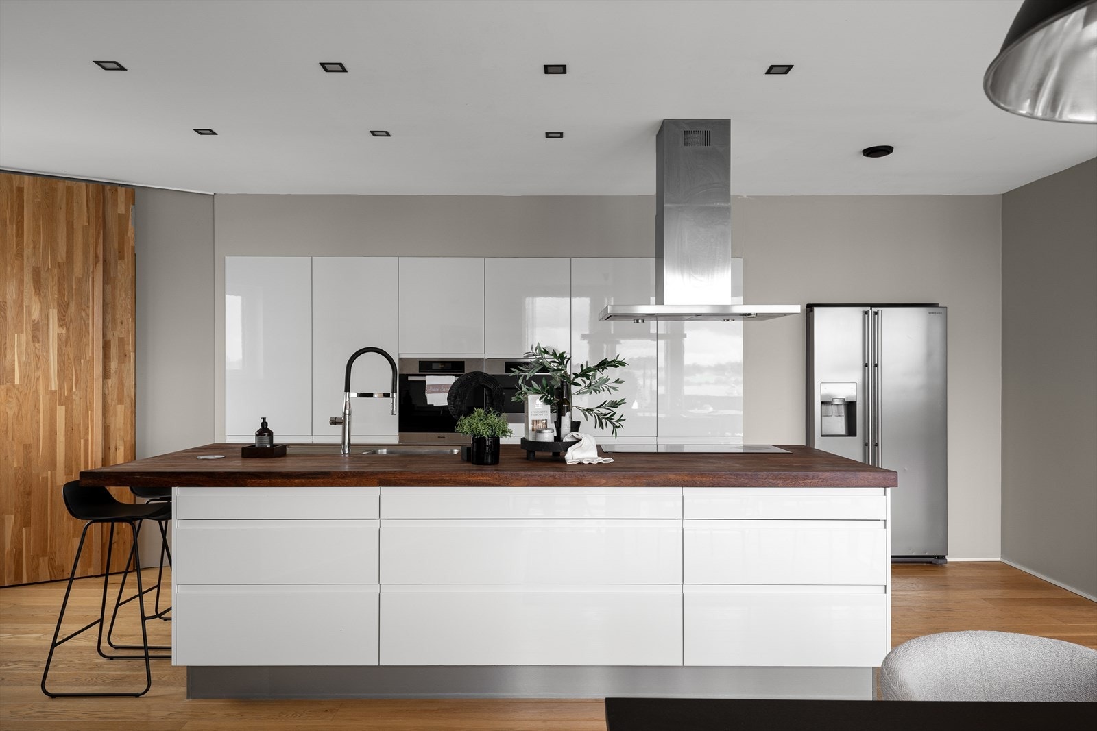 Moderne kjøkken med stor kjøkkenøy, integrerte hvitevarer og rikelig med skap- og benkeplass. Galleribilde