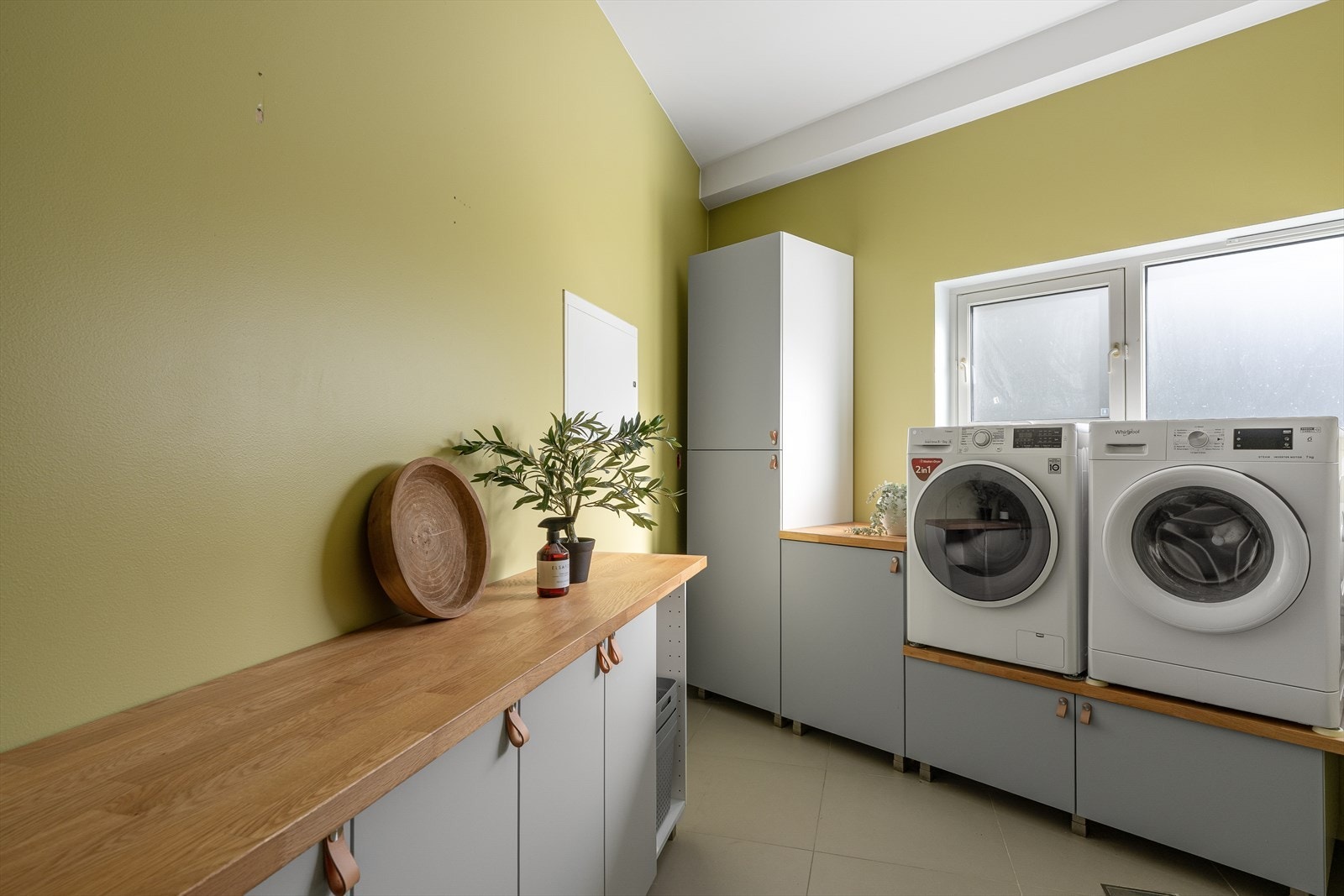 Praktisk vaskerom med god arbeidsbenk, rikelig oppbevaring og plass til både vaskemaskin og tørketrommel. Galleribilde