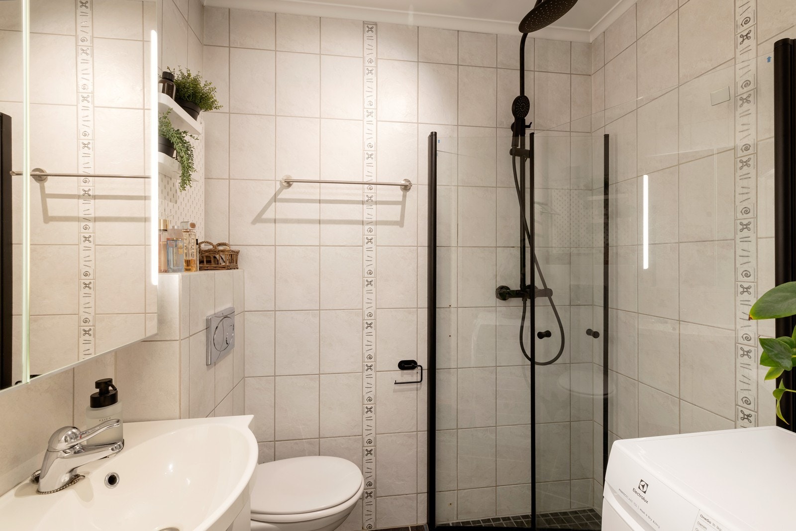 Flislagt bad med dusjhjørne, servant, wc og opplegg for vaskemaskin Galleribilde