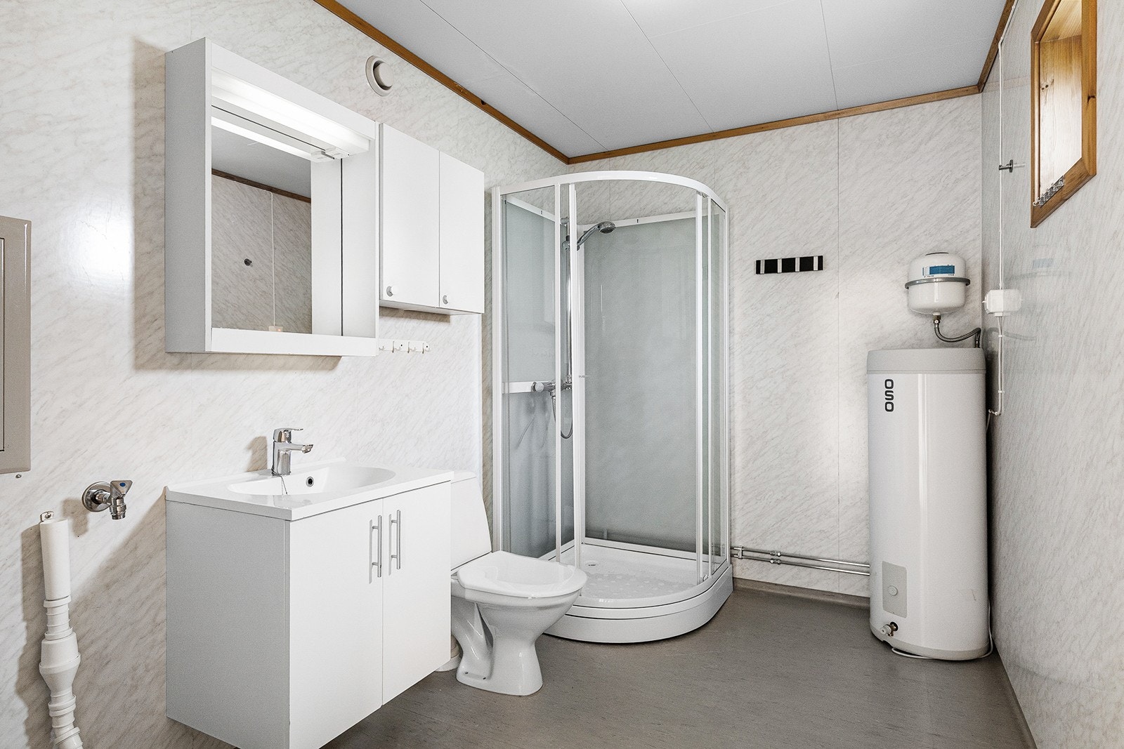 Baderommet er innredet med dusjkabinett, vegghengt servantskap, speil og vegghengt skap for oppbevaring, samt toalett. Her er det plass til vaskemaskin. Galleribilde