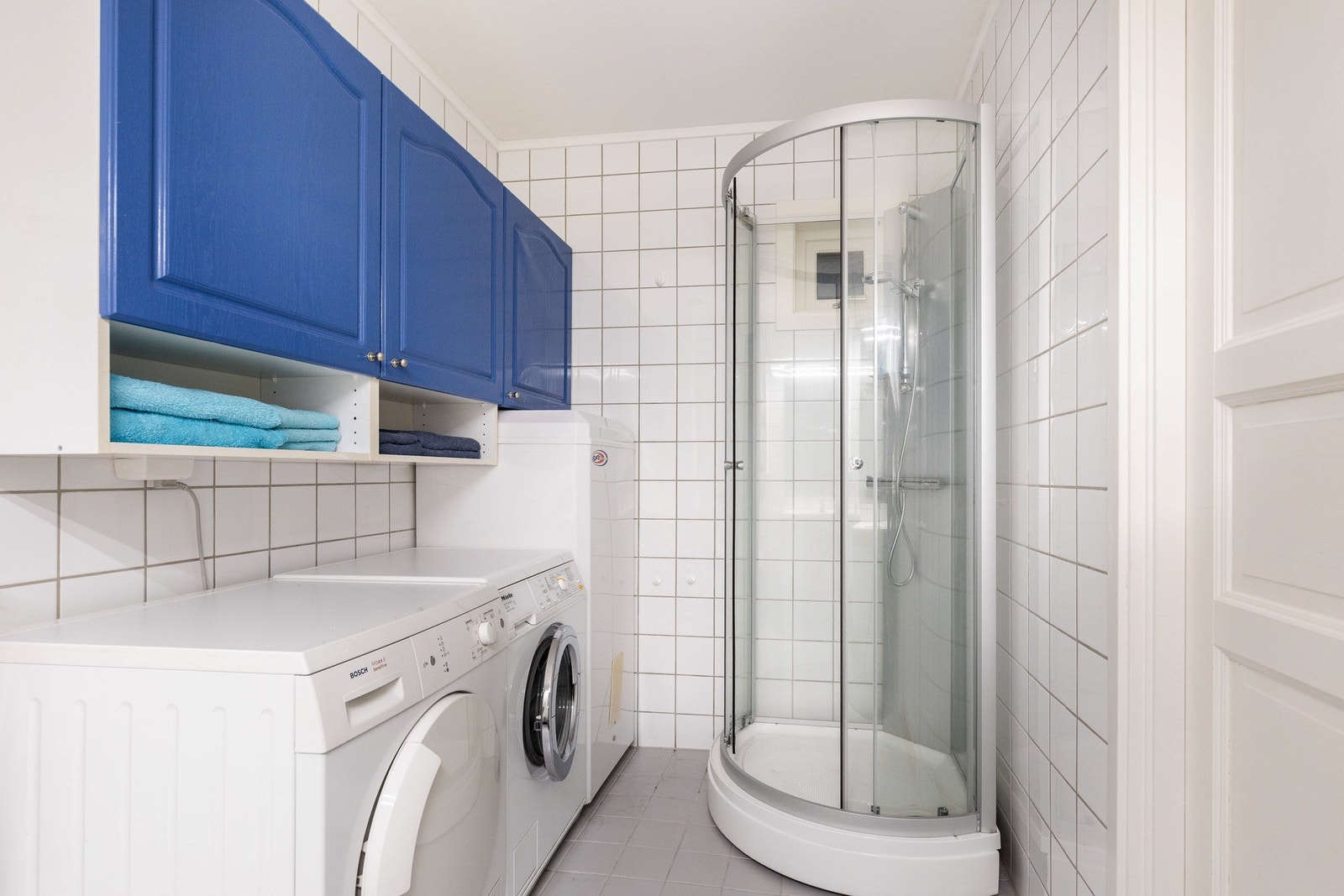 Rommet er innredet med baderomsmøbel med skap og skuffer, speil med belysning over servant, vegghengt toalett og dusjkabinett. Galleribilde