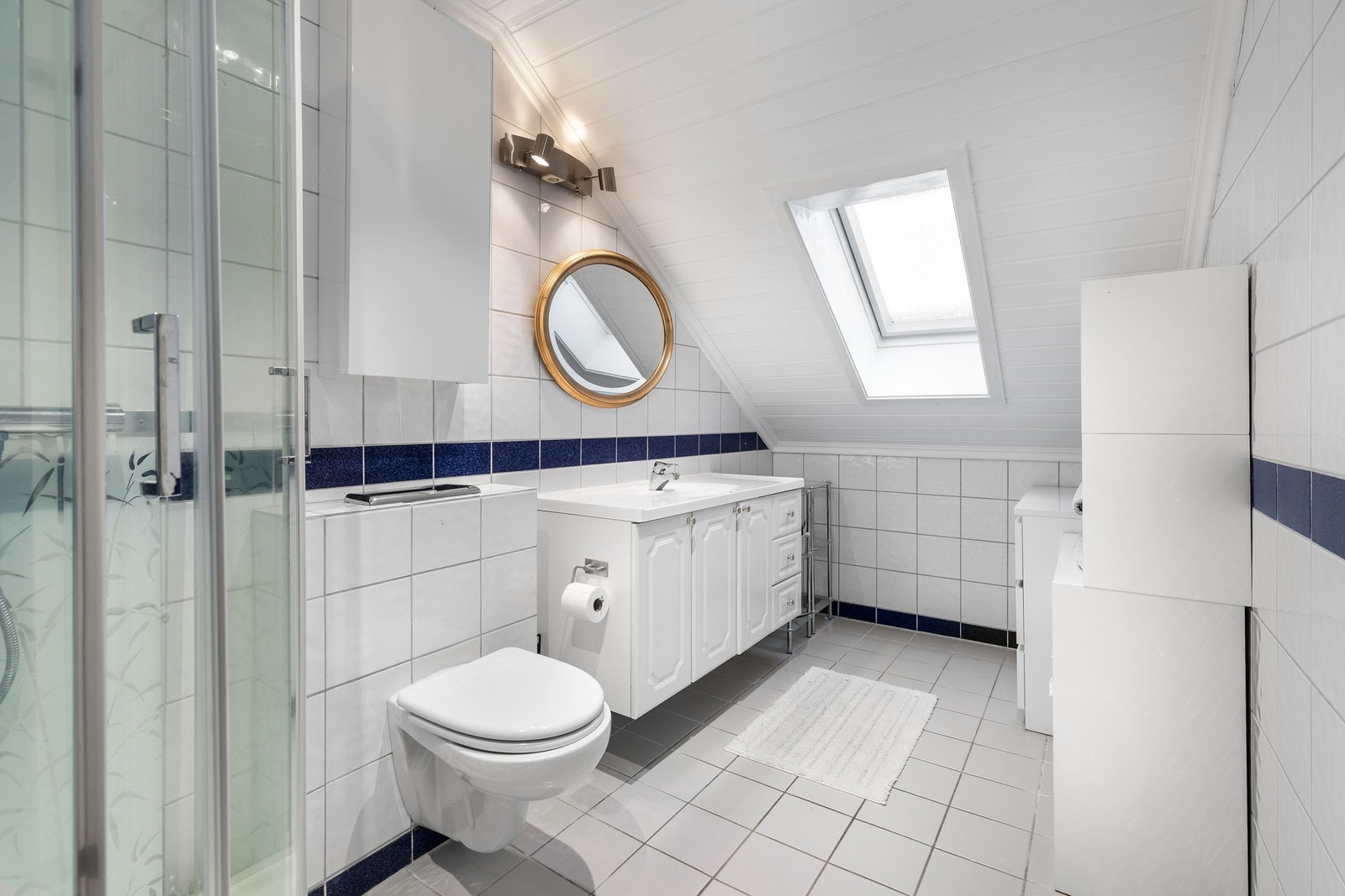 Badet i andre etasje har flislagte overflater i hvitt med blå detaljer. Galleribilde