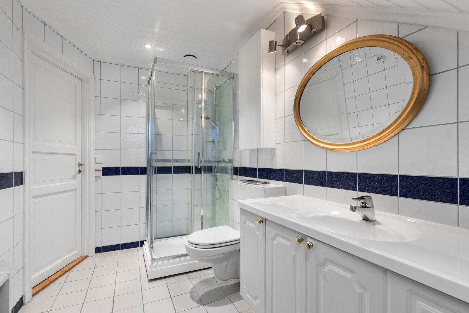 Her finner du baderomsinnredning i hvitt med skap og skuffer, speil over heldekkende servant samt praktiske oppbevaringsløsninger. Galleribilde