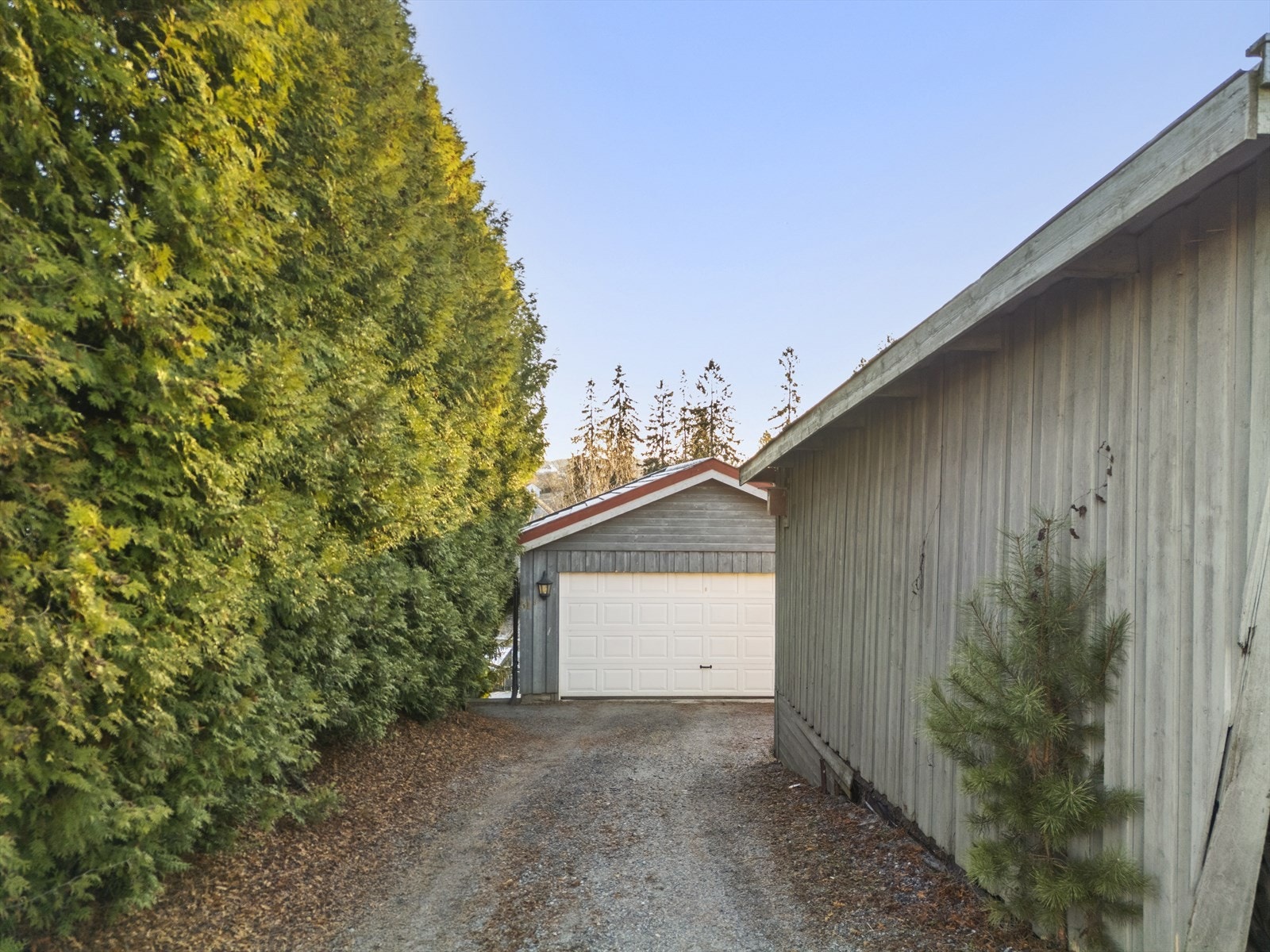 Gruset innkjørsel som leder frem til den frittstående dobbelgarasjen. Galleribilde