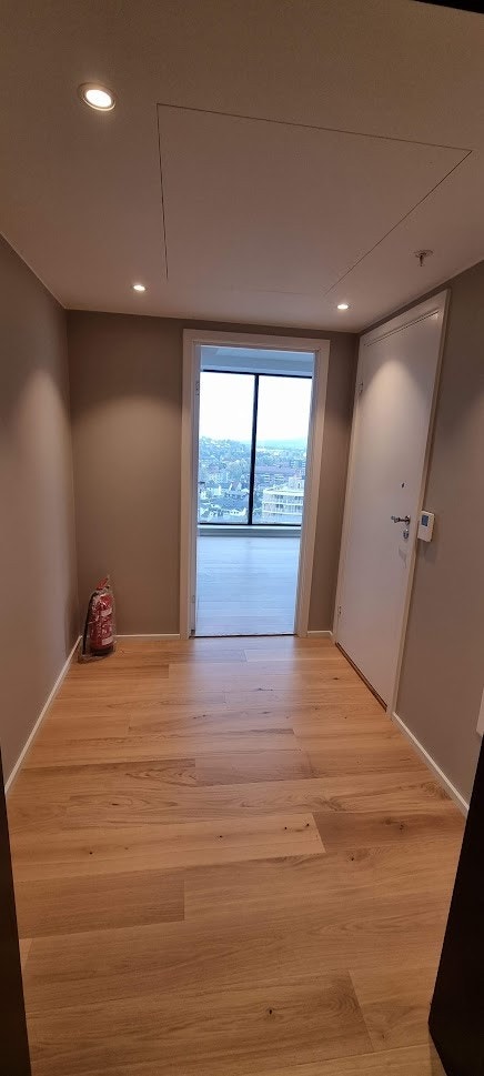 Entre med enstavs eikeparkett, lyse overflater og spotter i tak Galleribilde