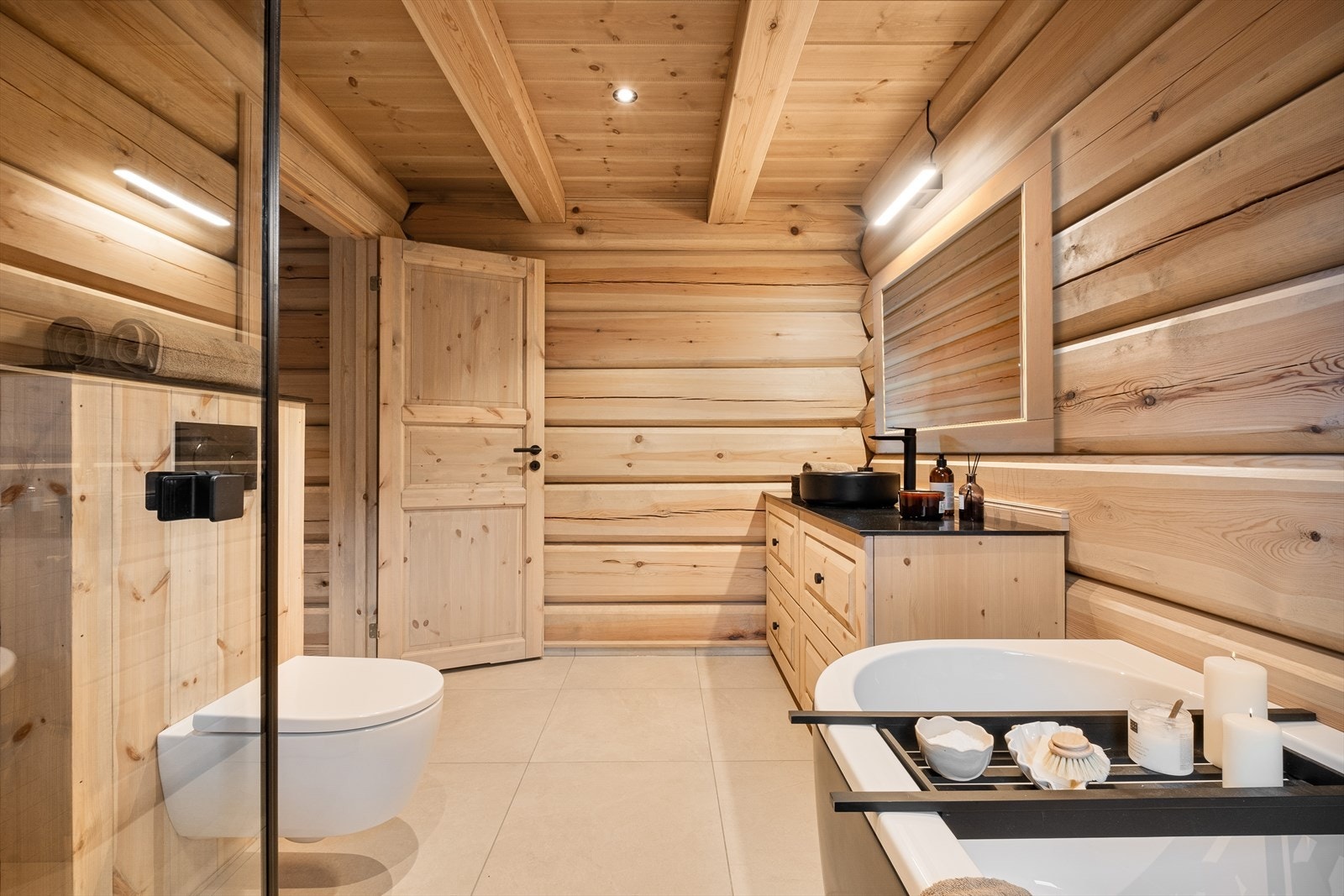 Badet er utstyrt med badekar, mekanisk avtrekk, dusjhjørne, innfellbare dusjdører, servantskap og veggmontert wc. Galleribilde