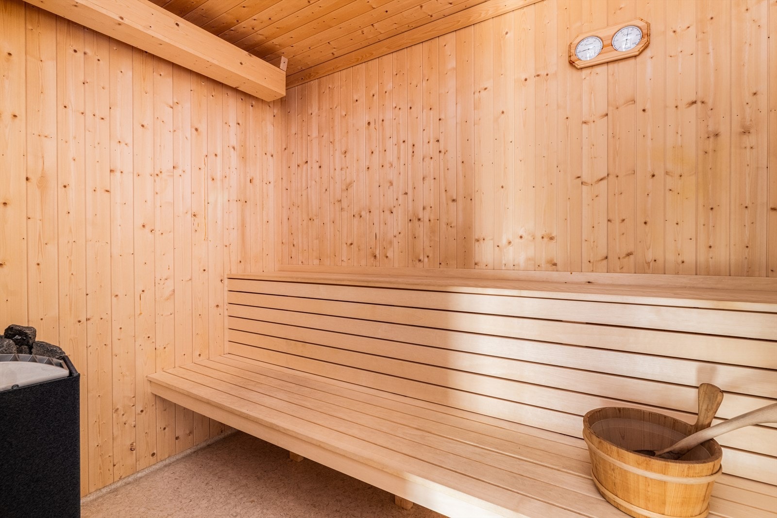 Tilkomst via en badstuedør inn til badstuen som har belegg på gulv, panel på vegger og i himling. Badstuen har plassbygde sittebenker i treverk og er utstyrt med badstueovn. Galleribilde