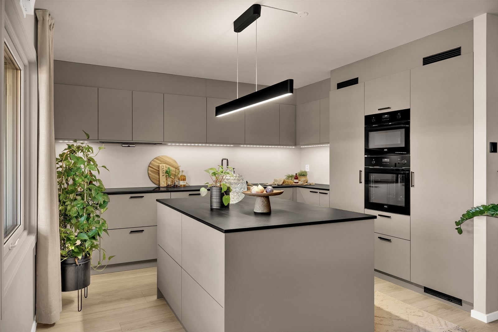 Romslig kjøkkenøy med sort benkeplate i Dekton-keramikk, som tåler høy varme og gir svært gode arbeidsforhold til matlagingen. Galleribilde