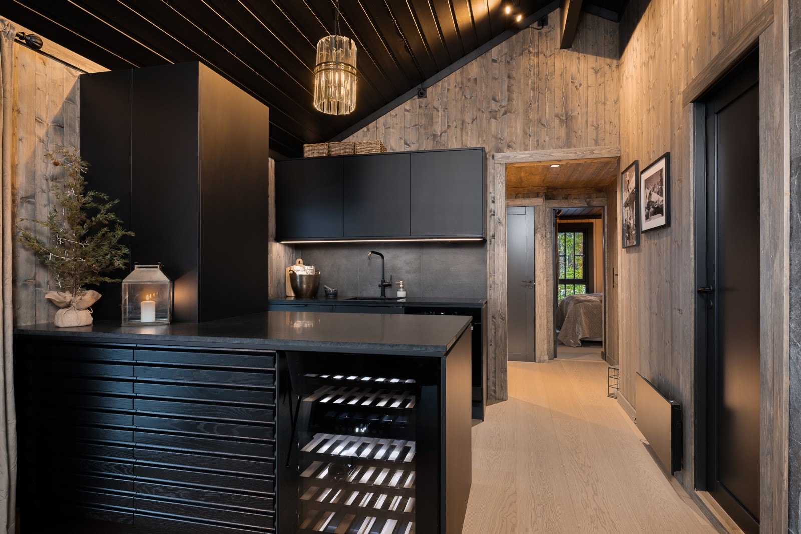 Lekkert kjøkken fra 2024 med sorte fronter og integrerte hvitevarer som vinskap, kjøl og fryseskap, oppvaskmaskin, komfyr og platetopp. Galleribilde