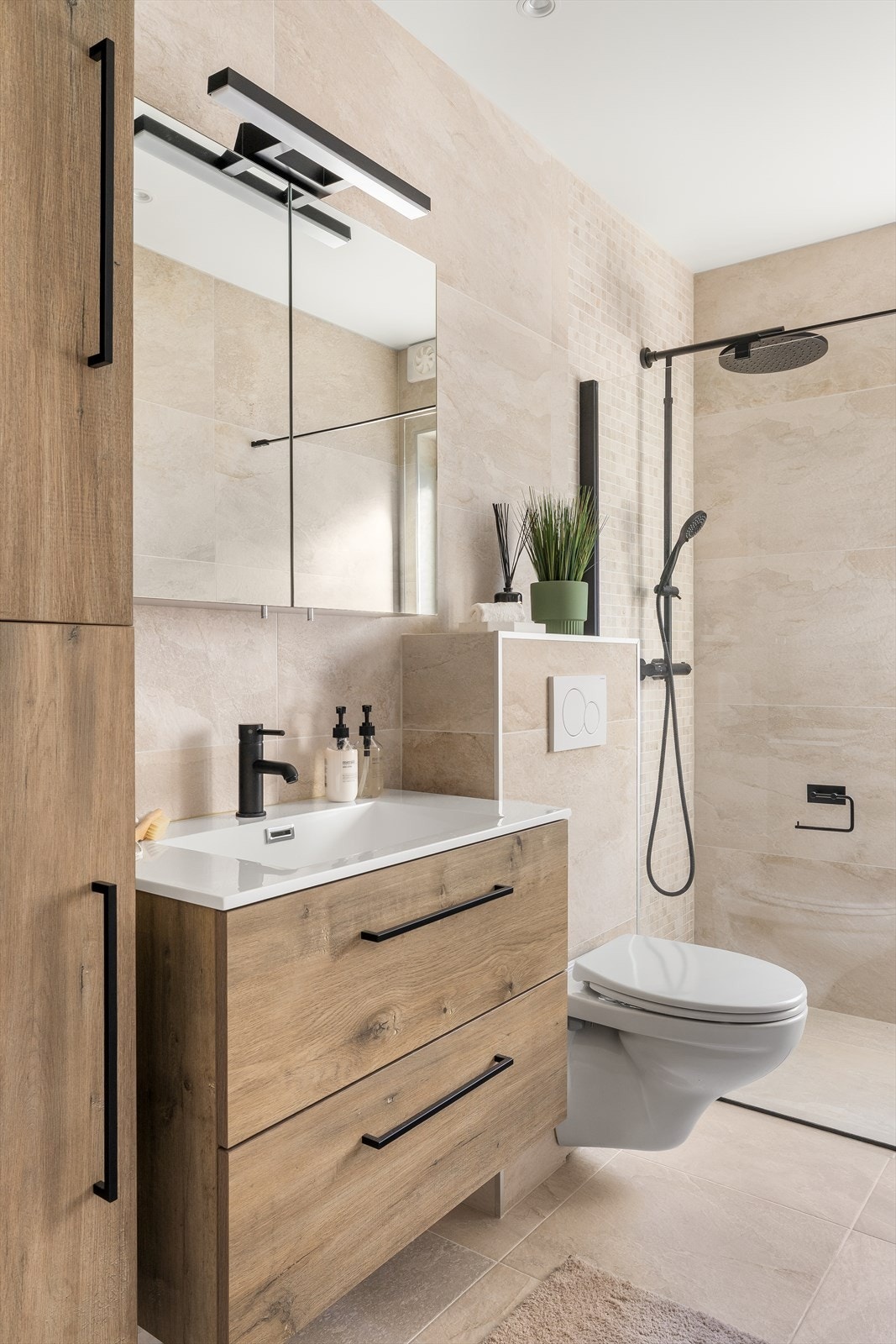 Baderomsinnredning med sorte detaljer, speilskap og et praktisk høyskap for oppbevaring. Galleribilde