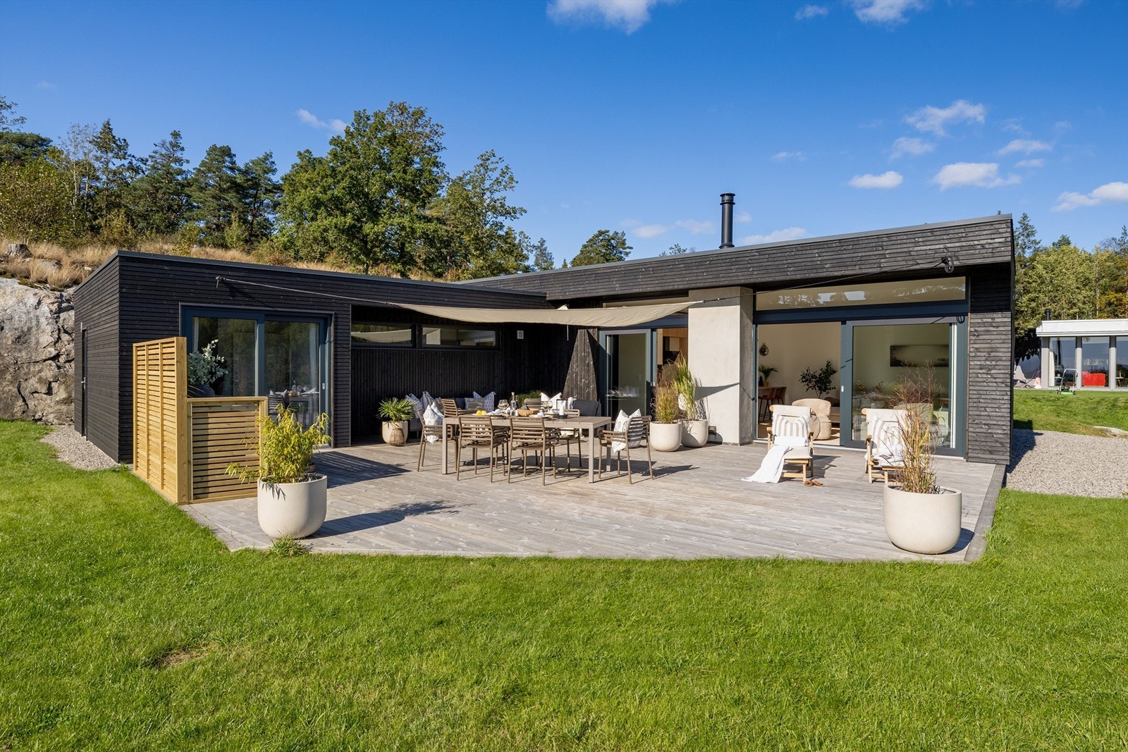 Arkitekttegnet funkis-hytte i L-form, designet for å omfavne uterommet og sjøutsikten. Galleribilde