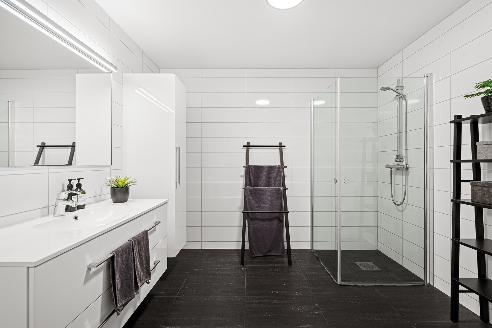 Stort, helfliset bad med stilrent uttrykk. Hvite veggfliser og mørke gulvfliser gir et moderne og tidløst uttrykk. Galleribilde