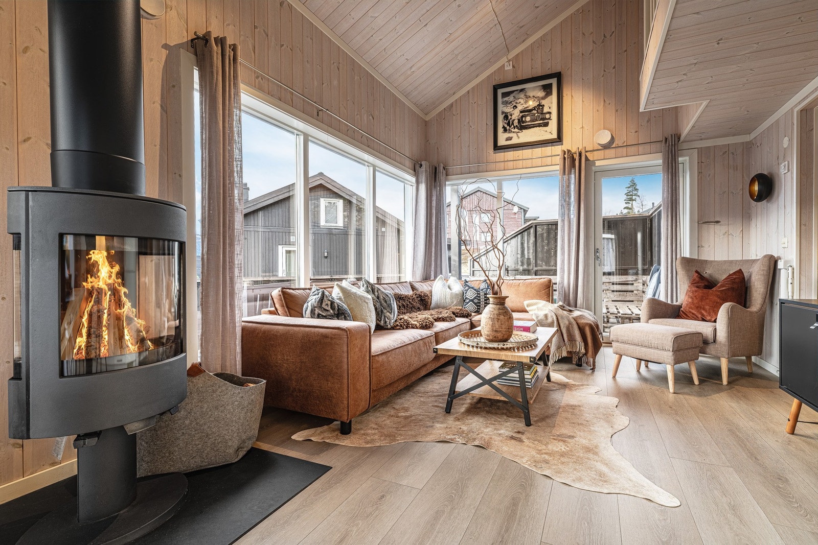 Lys og innbydende stue med peisovn, store vinduer som gir rikelig med naturlig lys, perfekt for avslapning og sosiale sammenkomster Galleribilde