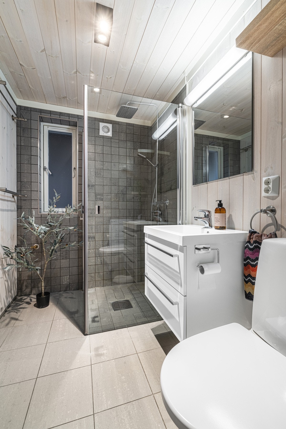 Stilrent baderom med moderne dusjløsning. Lyse fliser og naturlig lys gir en behagelig atmosfære. Galleribilde