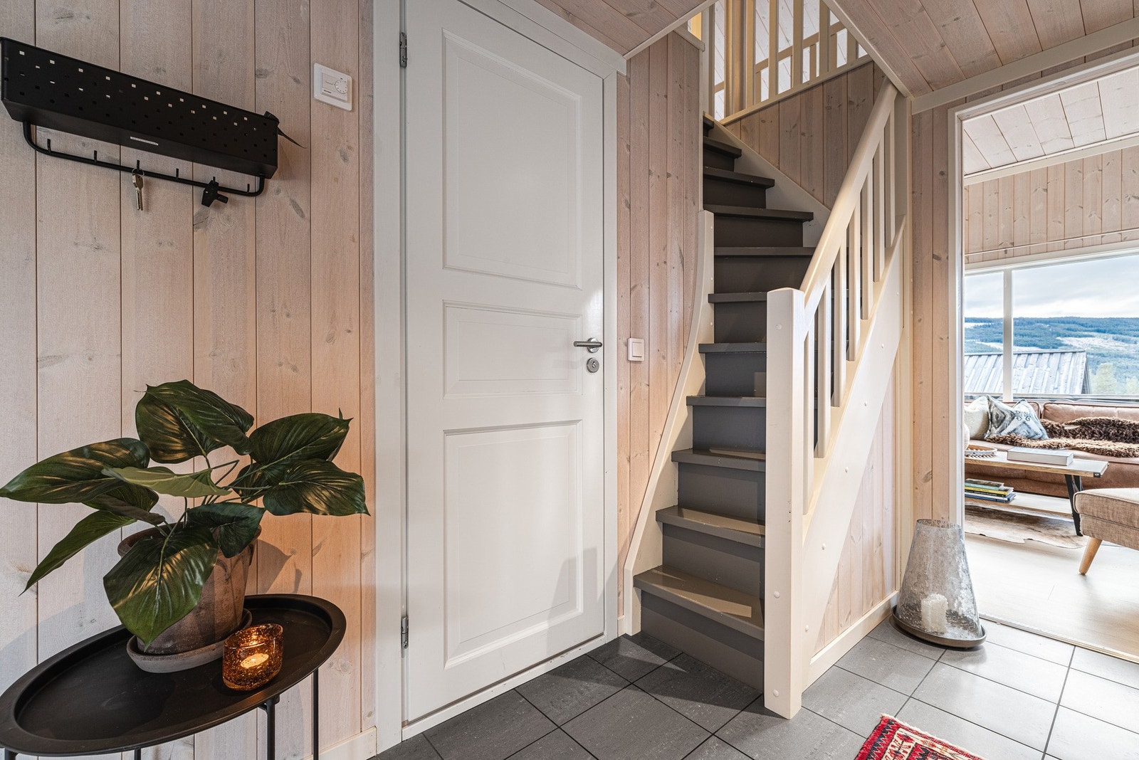 Romslig flislagt gang med trapp opp til hemsen. Galleribilde