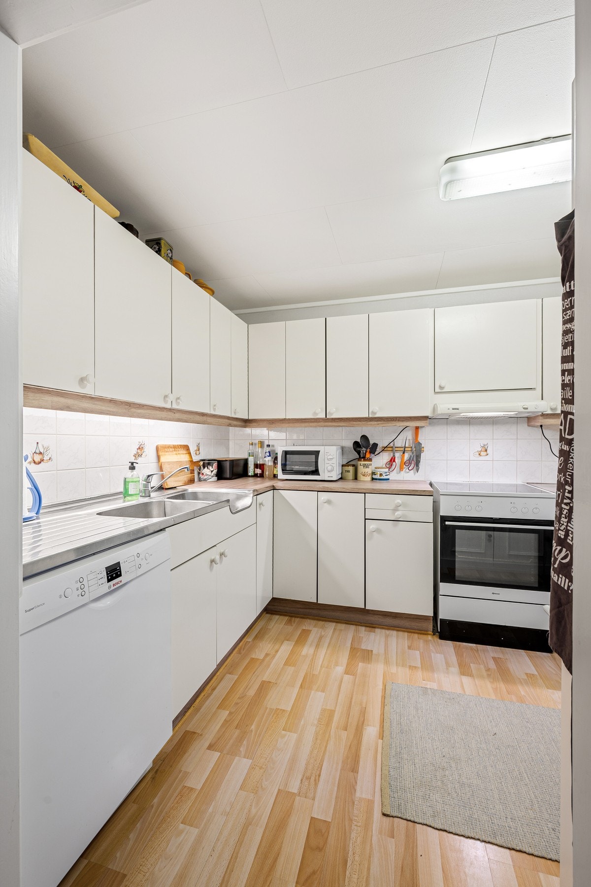 Kjøkken med hvite, slette fronter og godt med skap- og benkeplass Galleribilde