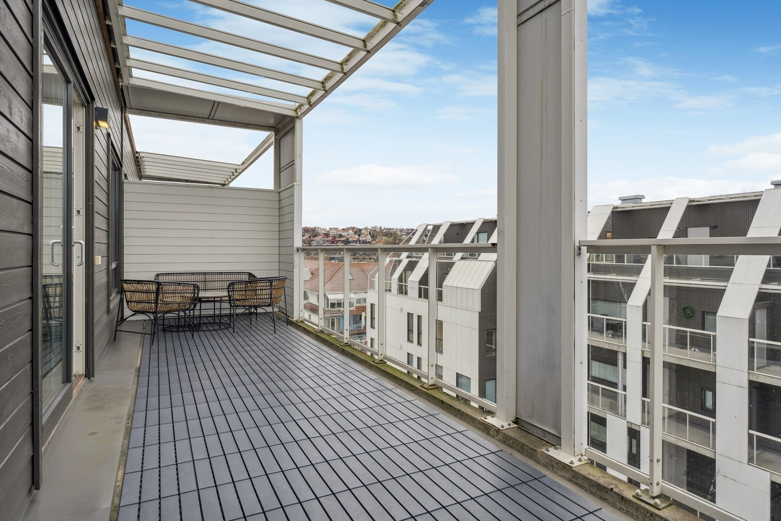 Balkongen er overbygd, har dekke med terrasseflis og rekkverk av glass og stål. Galleribilde