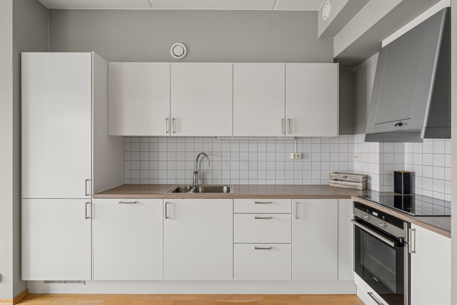 Kjøkkeninnredningen, som er fra byggeåret, har hvite, slette fronter og benkeplate i laminat. Fliser som backsplash og god skapplass. Galleribilde