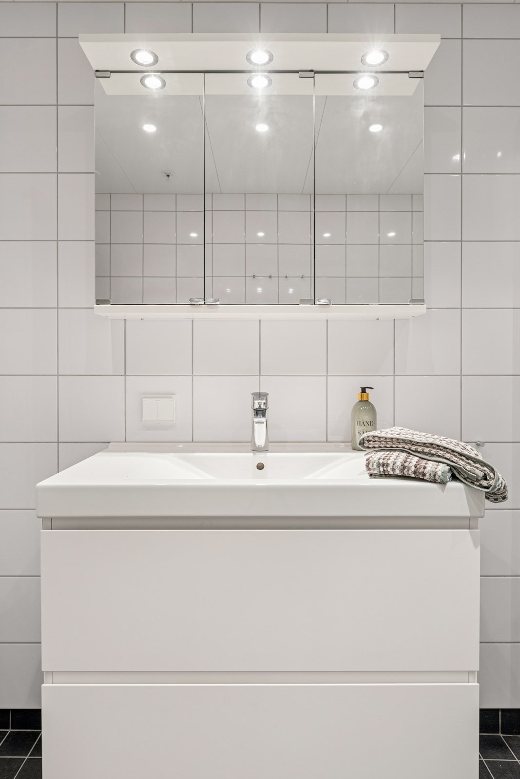 Vegghengt baderomsmøbel med vask og praktisk speilskap med belysning over. Galleribilde