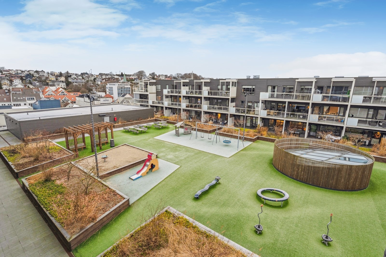 Leiligheten har tilgang til et felles uteområde med lekeplass og sittegrupper, ideelt for sosialt samvær. Galleribilde