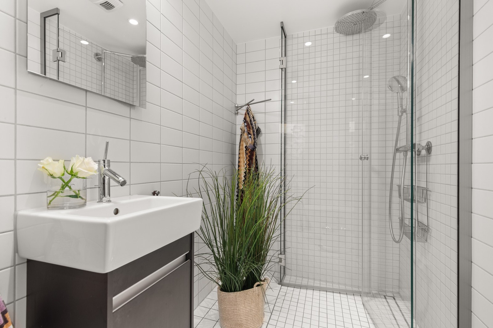 Bad v/ gang: Flislagt baderom med vegghengt klosett, dusjhjørne og servantinnredning. Galleribilde