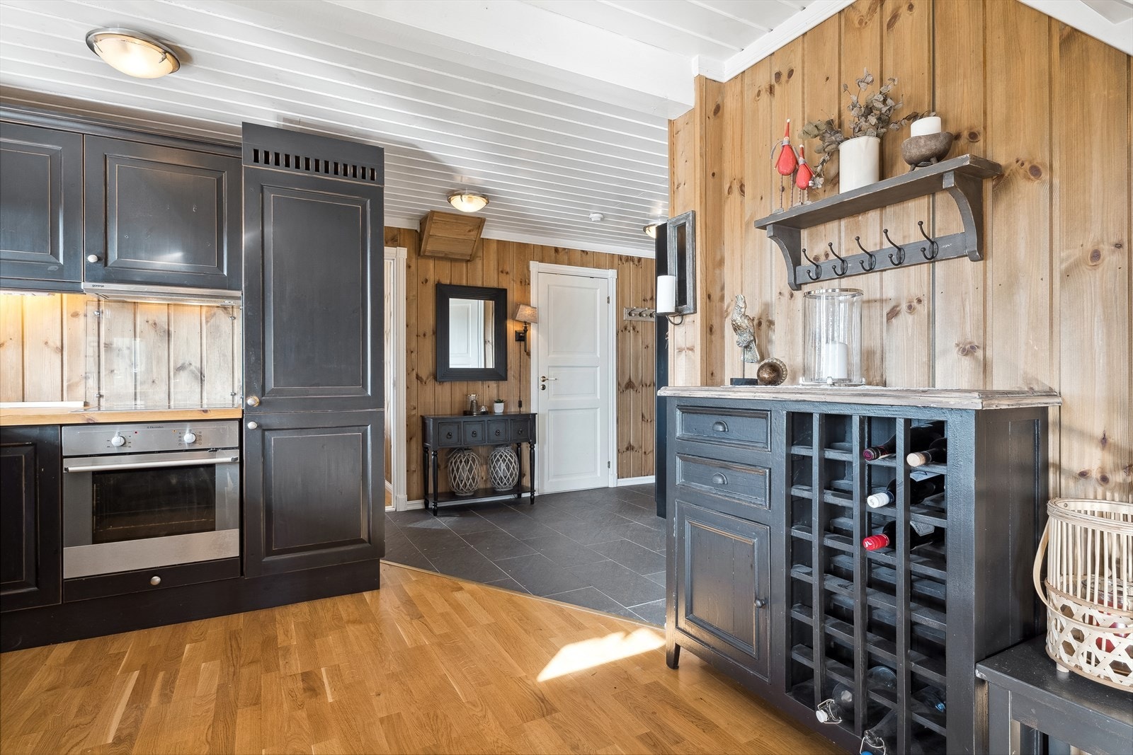 Gjennomført og helhetlig stil med behandlede panelvegger, hvitmalte himlinger, parkett og fliser på gulvene. Galleribilde