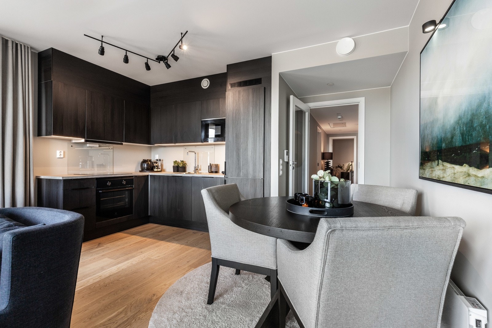 Skap og skuffer har fronter av mørk trefiner, benkeplatene er i lys laminat og det er montert ledbelysning. Galleribilde