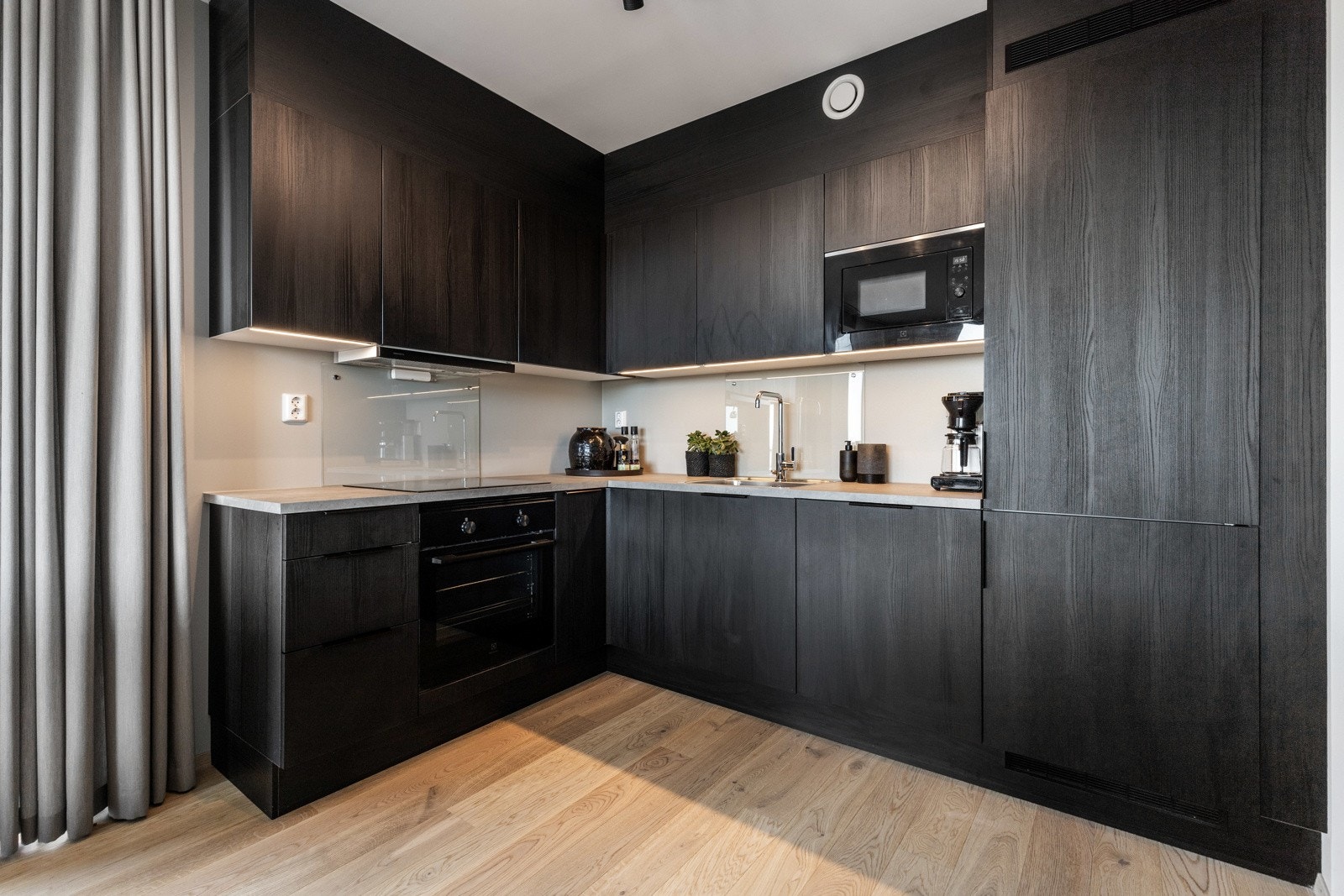 I benken er det planlimt oppvaskkum og integrert induksjonstopp, og veggene bak er beskyttet med glassplater. Galleribilde