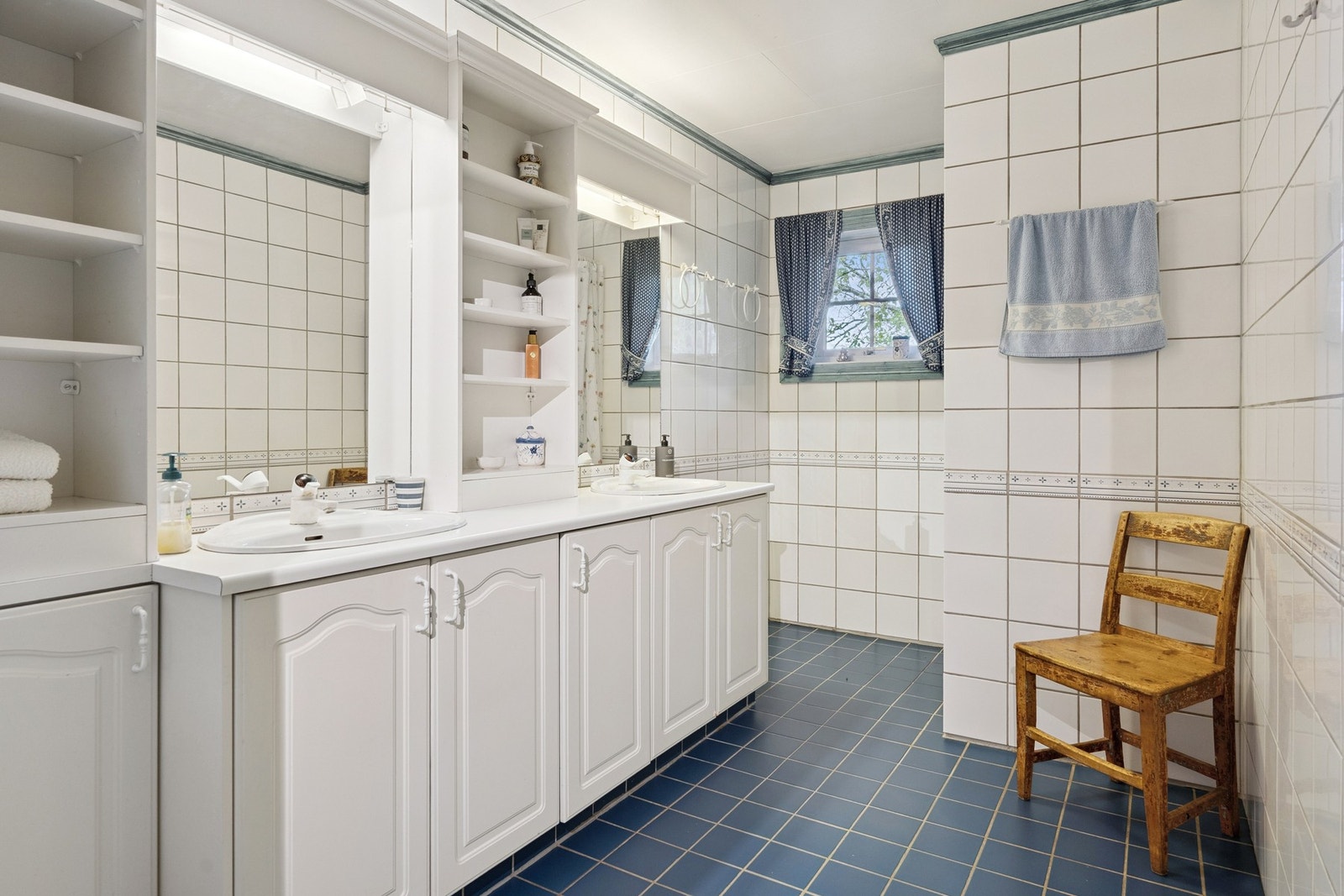 Badet har fliser på vegg og gulv med varmekabler. Innredning med to servanter og dusjnisje med forheng. Galleribilde