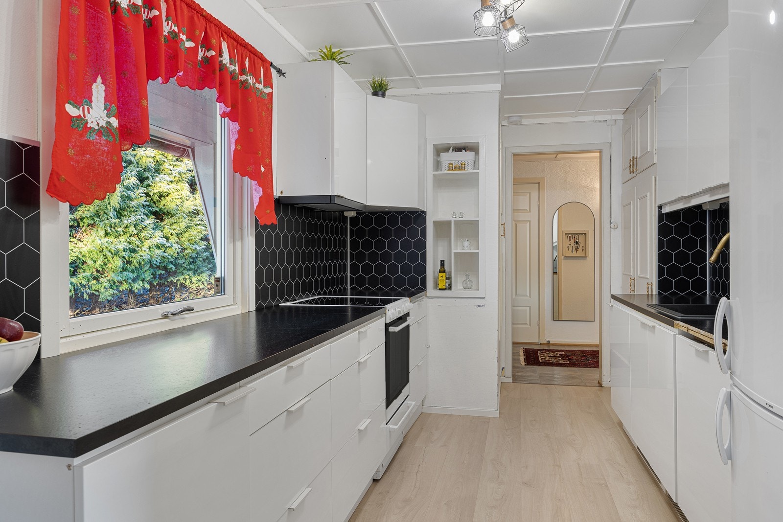 Kjøkkeninnredningen er tidløs, med hvite, glatte fronter, nedfelt oppvaskkum og laminert benkeplate i sort utførelse. En oppvaskmaskin er integrert i innredningen. Galleribilde