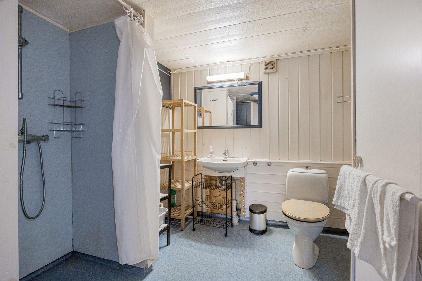 Badet i underetasjen er innredet med linoleumsbelegg på gulvet. Veggene er kledd med våtromsplater og lysmalt trepanel. Galleribilde