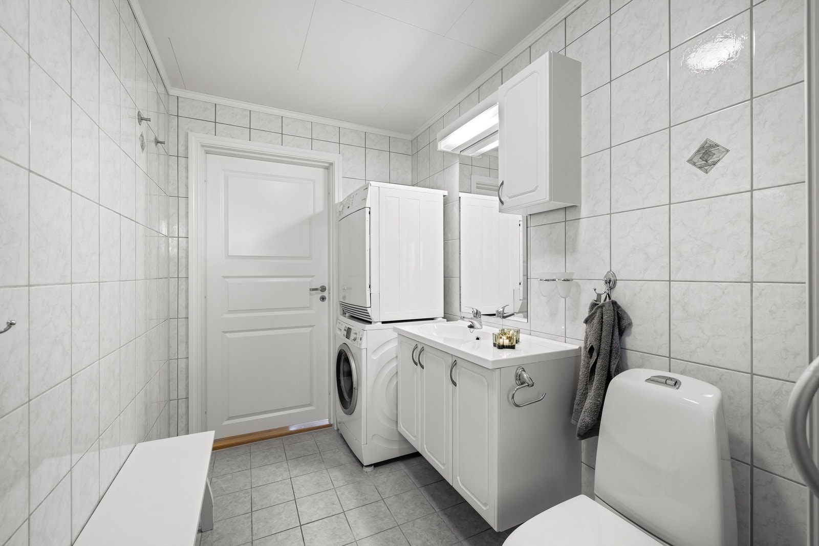 Badet er innredet med vegghengt servantskap, dusjnisje med skyvedører, gulvmontert toalett, samt plass og opplegg for vaskemaskin og tørketrommel. Galleribilde