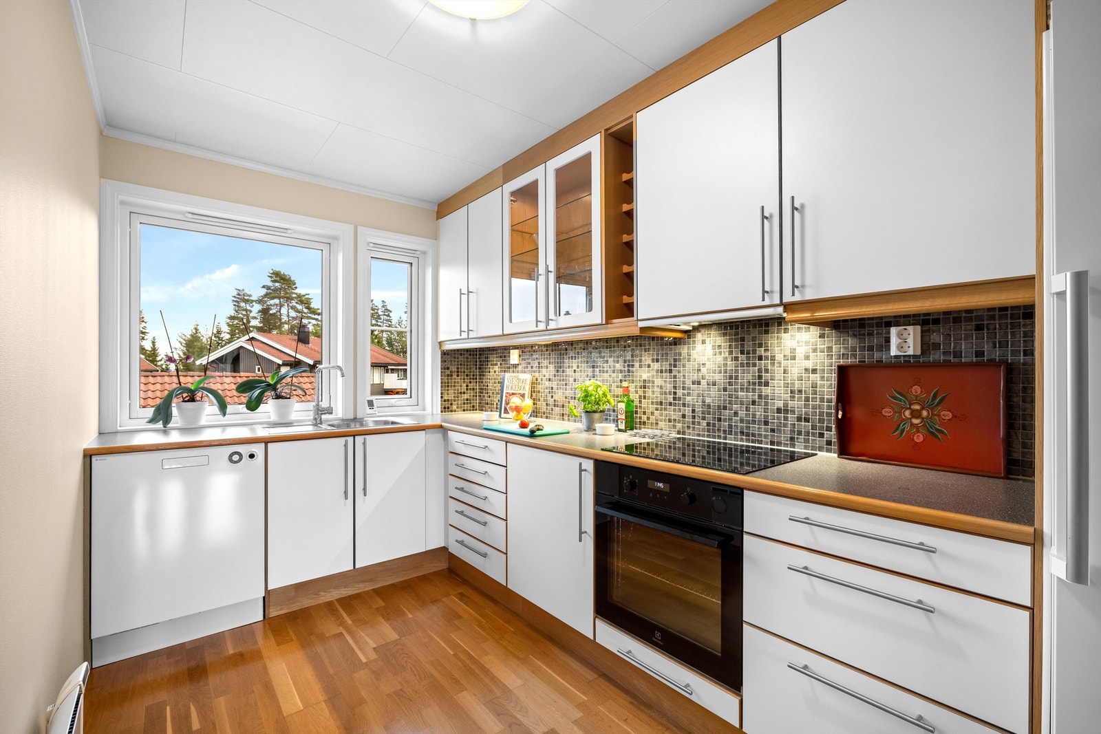 Kjøkkenet har glatte fronter, laminert benkeplate og praktiske fliser mellom benk og overskap. Galleribilde