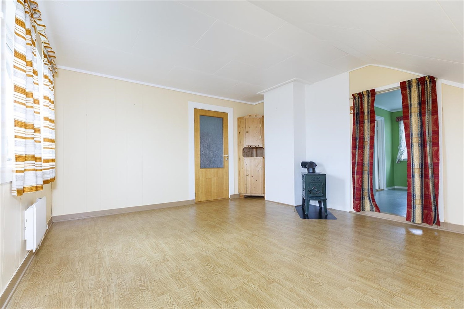 En lys stue med en vedovn og plass til sitteplass. Galleribilde