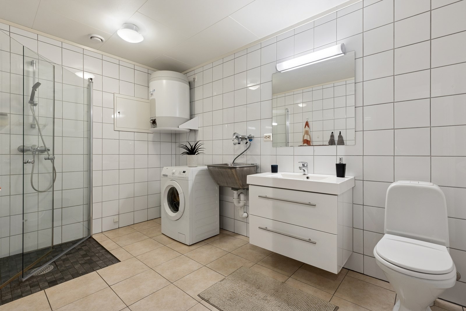 Flislagt baderom med tidløst uttrykk som kombineres med vaskerom. Galleribilde