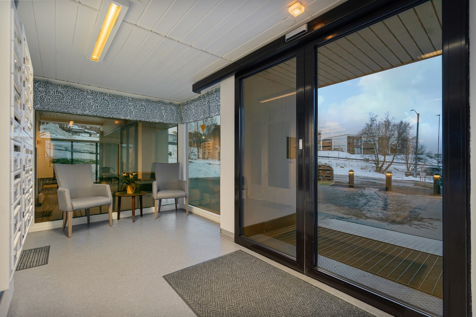 Hyggelig og pent felles inngangsparti med sitteplasser og postkasser Galleribilde