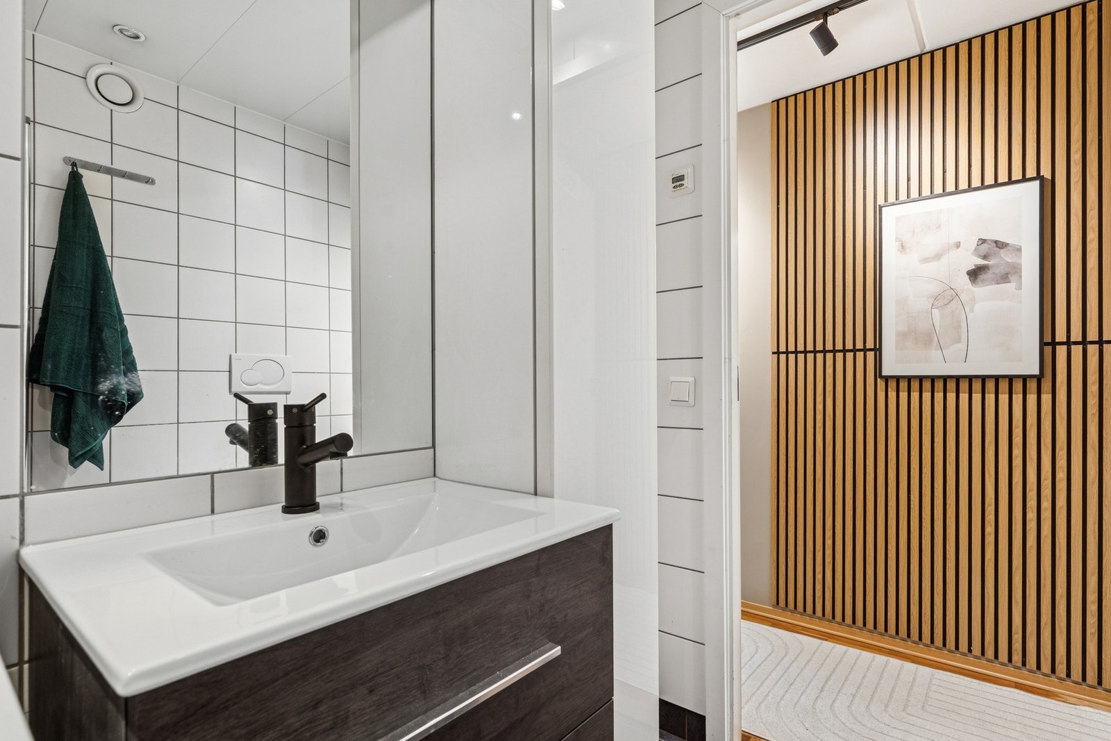 Badet er et prefabrikkert bad fra byggeår, utført med flislagt gulv og vegger, elektrisk gulvvarme og malt himling med downlights. Galleribilde