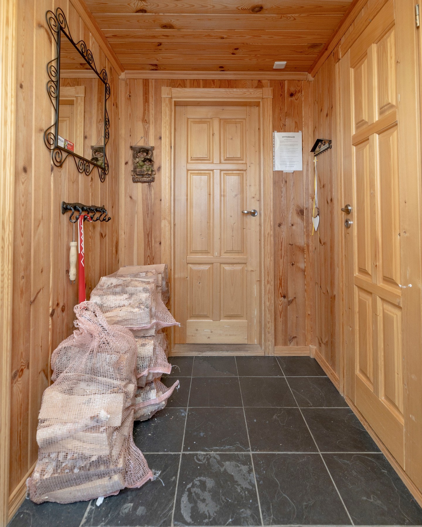 Praktisk entré med flislagt gulv og varmekabler. Vegger og himling i trepanel gir et lun og gjennomført hyttepreg, med god plass til yttertøy og vedoppbevaring. Galleribilde