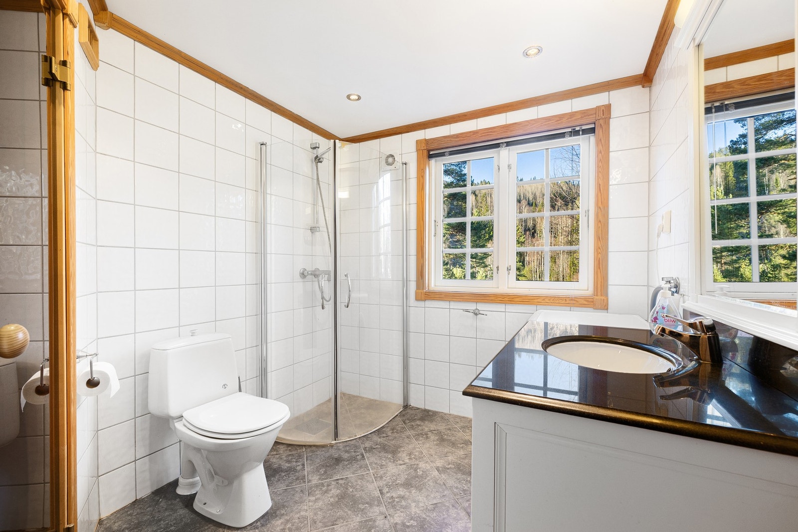 Romslig hovedbad med inngang til badstue. Badet er innredet med dusjhjørne med glassdører, gulvmontert toalett og baderomsinnredning med nedsenket servant og speil. Galleribilde