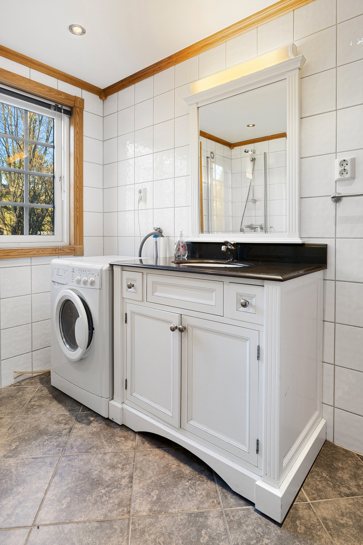 Bad/toalettrom innredet med dusjhjørne med foldedører i glass, vegghengt toalett og baderomsinnredning med nedsenket servant og speil. Galleribilde