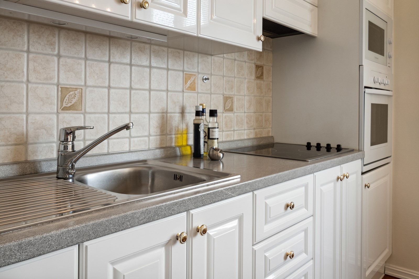 På kjøkkenet finner du laminat benkeplate med nedfelte kummer og en flislagt vegg mellom benkeplate og overskap. Galleribilde