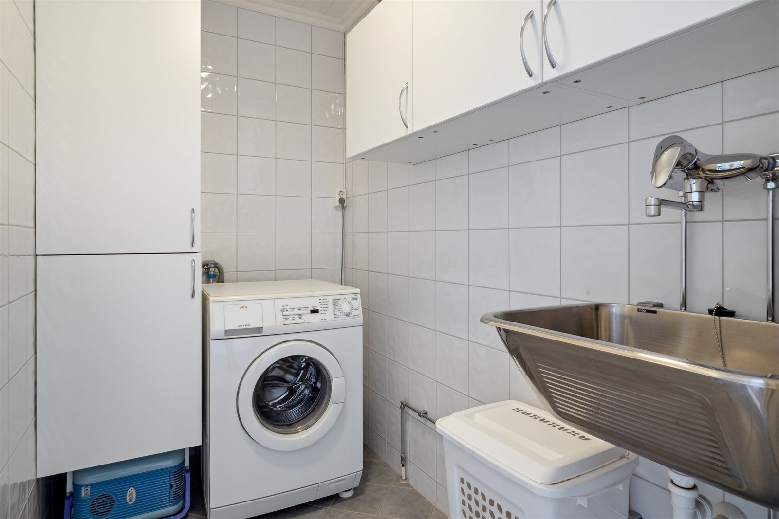 Flislagt vaskerom med varme i gulv. Rommet har innredning med skap og utslagsvask, samt opplegg for vaskemaskin. Galleribilde