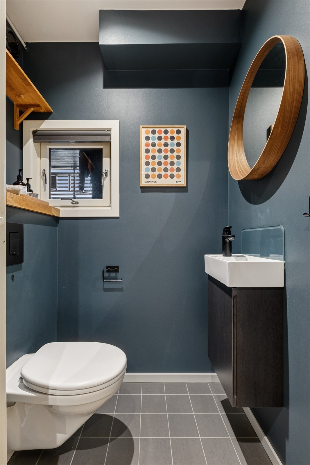 Toalettrommet har fliser på gulv, malte plater på vegger og tak, og er innredet med vegghengt toalett og servant. Galleribilde