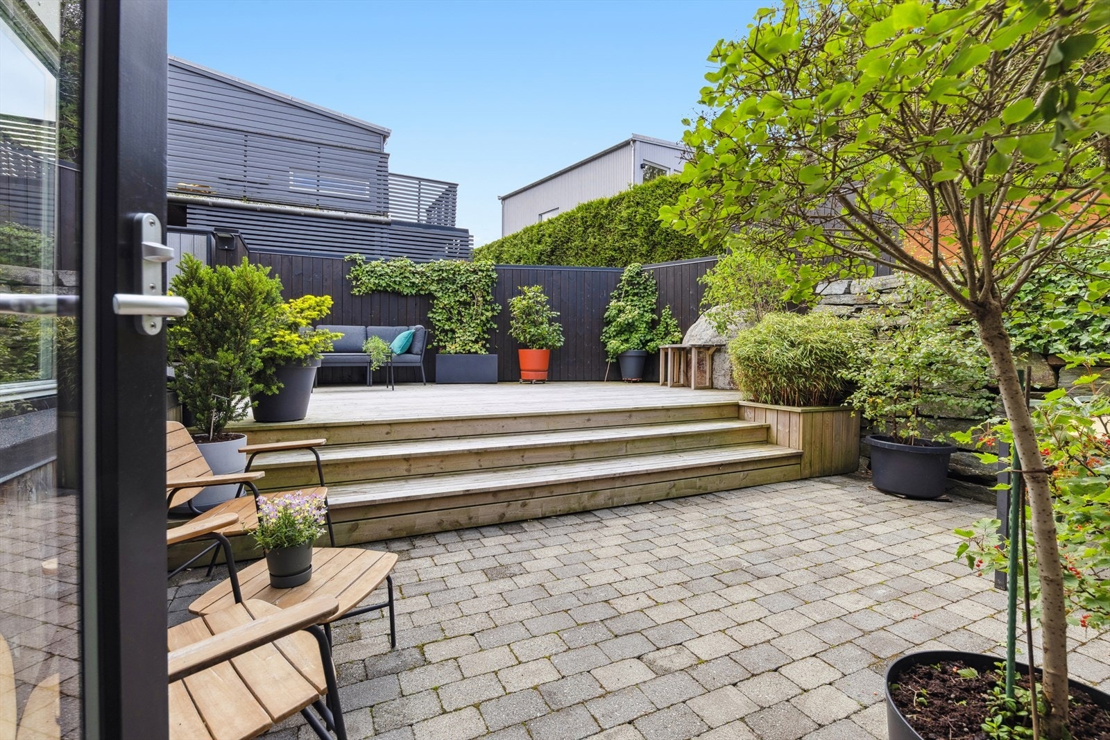 Uteområdet byr på plenlagt hage, terrasse med belegningsstein og tredekke - perfekte rammer for både hverdagsliv og sosiale sammenkomster. Galleribilde