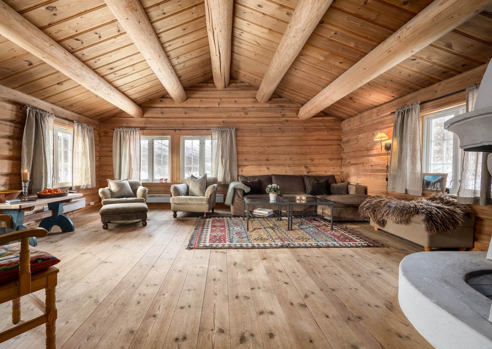 Lun stue i laftet tømmer, med store vindusflater som slipper naturen og den vide utsikten i Mørekvamdalen rett inn i stua. Galleribilde